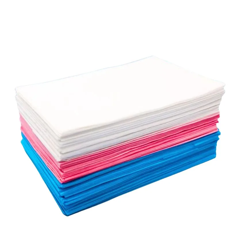 Disposable non-woven bed sheets in white, pink and blue stacked for massage table
